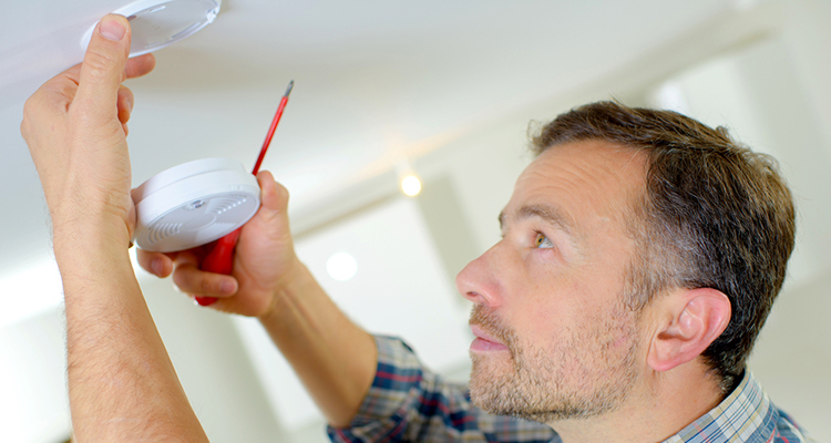 Man testing smoke alarm for daylight savings time 